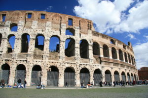 Roman Colosseum in Rome, Italy with blue sky and light clouds and people walking and exploring the colosseum