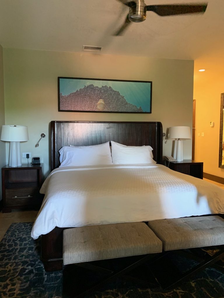 Sandals Grenada Room with a King Size Bed along with a foot bench and two lamps along with a fan